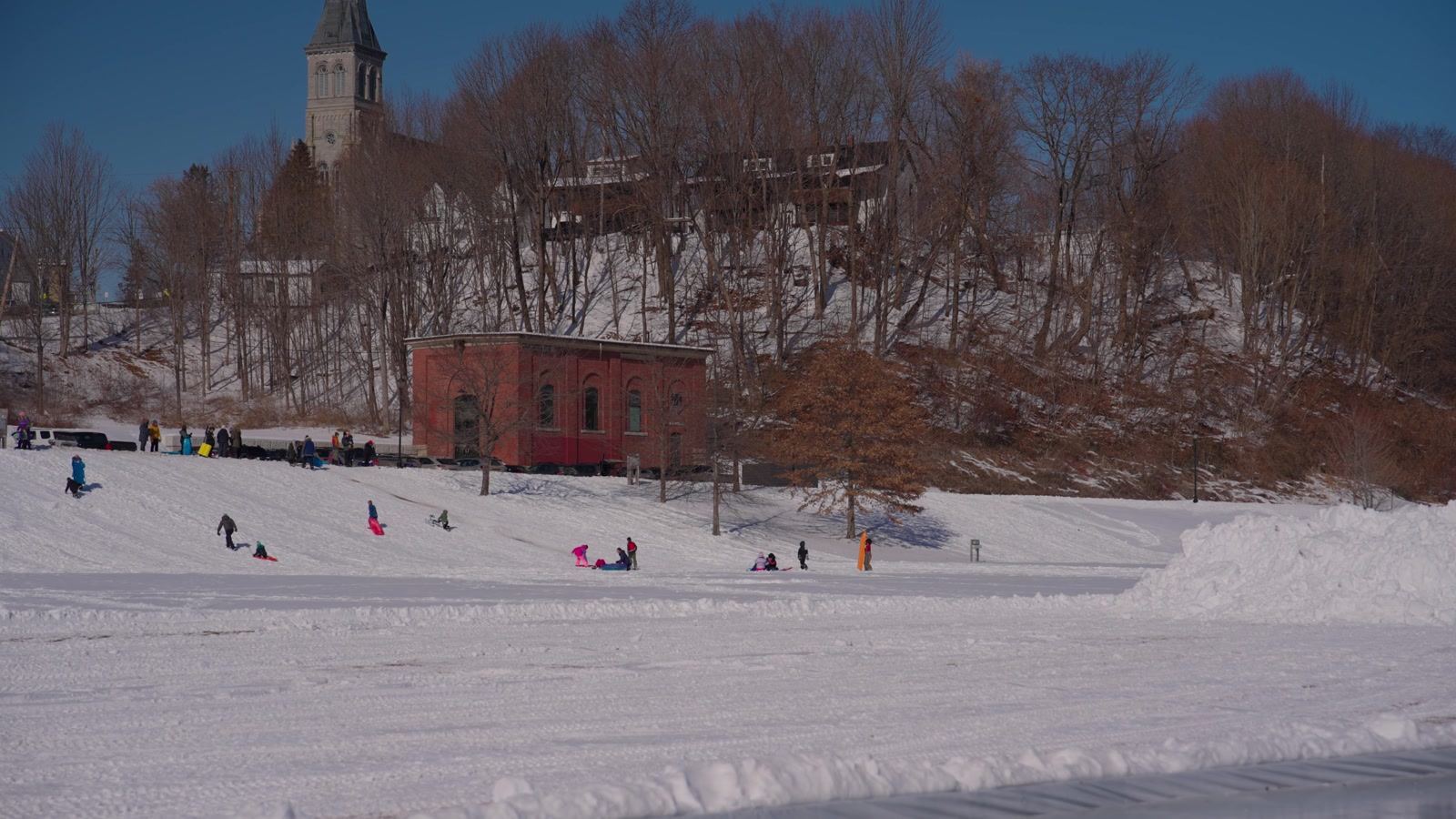 People sledding on a snowy hill at a park in Augusta, Maine