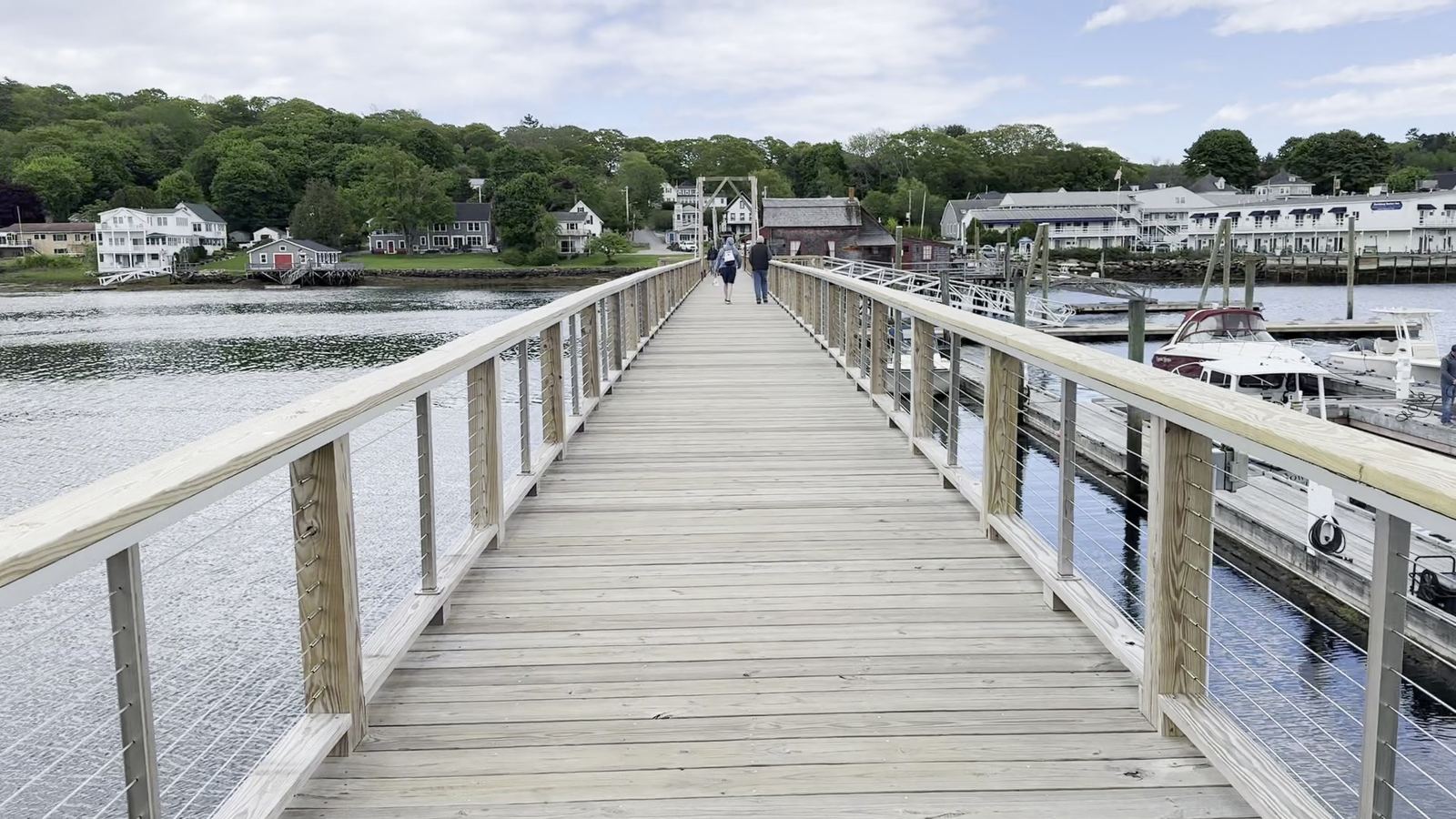 People walking across the wooden footbridge in Boothbay Harbor, Maine, in June
