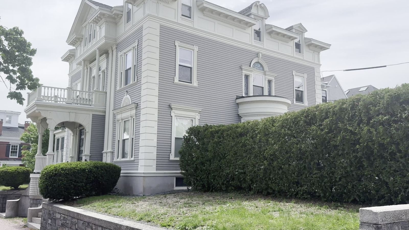 A grey Second Empire house with a mansard roof on a street in Portland, Maine